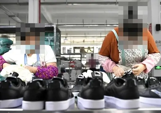 Operarias revisando zapatillas negras en una línea de fábrica