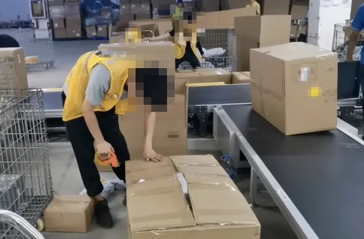 Trabajador cerrando cajas de envío junto a una cinta transportadora